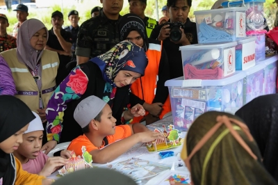 Queen visits Johor flood victims at two relief centres, distributes aid